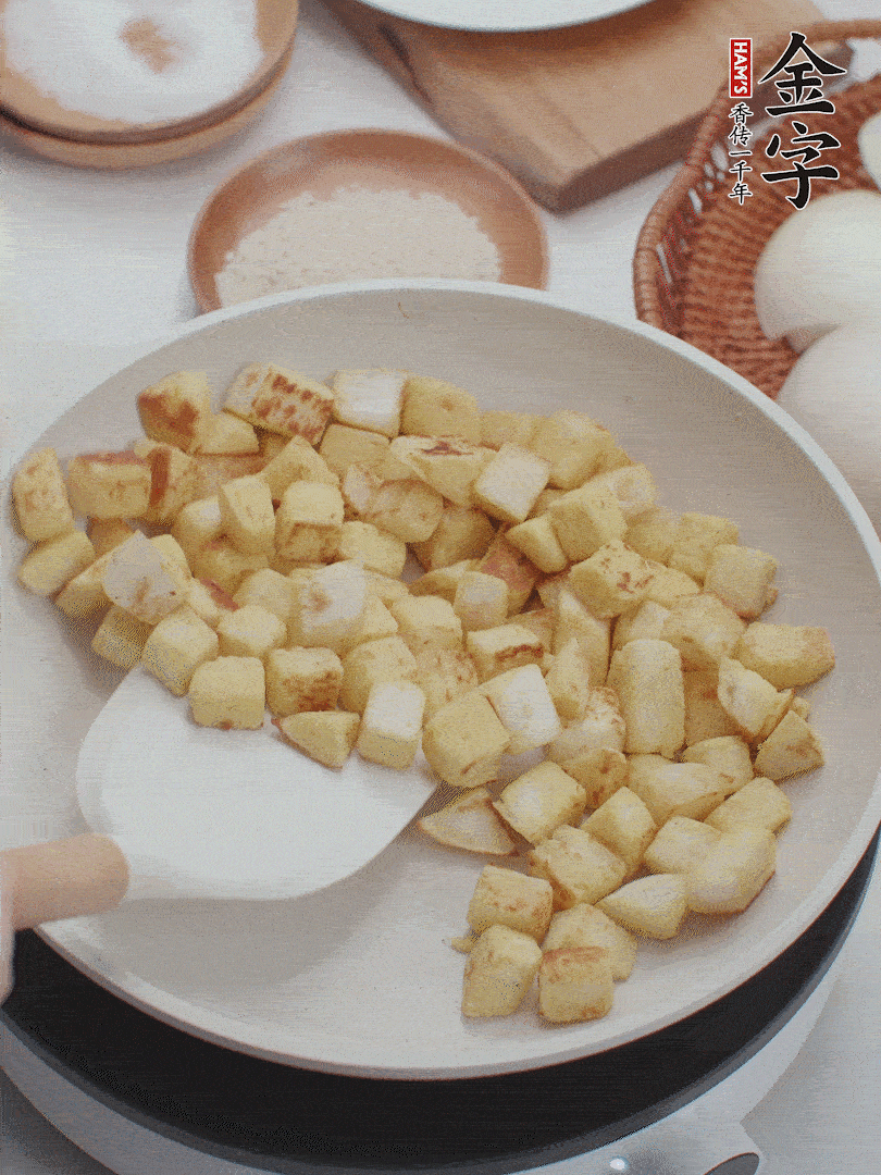 起鍋熱油，倒入饅頭丁，小火煎至蛋液凝固定型再翻面，饅頭丁部煎至金黃時盛起待用。